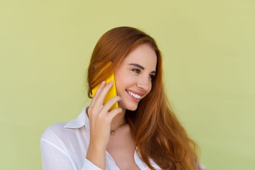 Beautiful red hair woman in casual shirt on green background talk on mobile phone smile and laugh