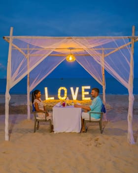 Romantic dinner on the beach in Phuket Thailand, couple man and woman mid age Asian woman and European man having dinner on the beach in Thailand during sunset.