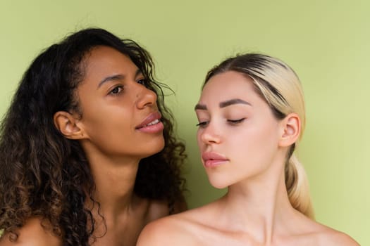 Woman close beauty portrait mixed race black skin and white skin, two female on green background