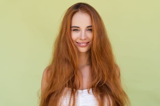 Beauty portrait of young topless red hair woman with bare shoulders on green background long strong shiny orange hair