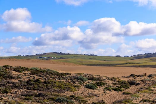 Distant ranch on green rolling hills by sand dunes on sunny day in Point Reyes., California High quality photo