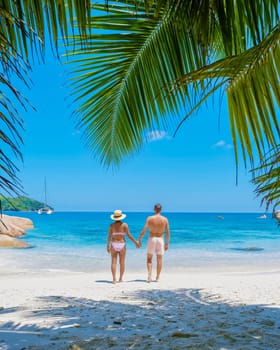 Anse Lazio Praslin Seychelles, a young couple of men and women on a tropical beach during a luxury vacation in Seychelles relaxing on the beach with palm trees