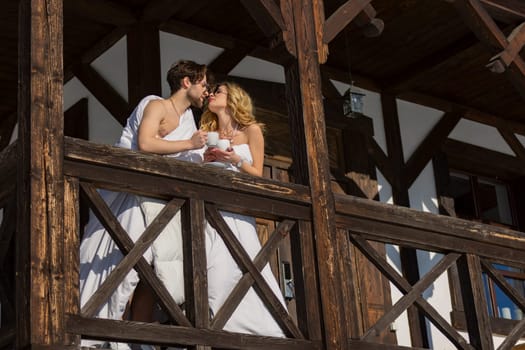 couple wrapped in blankets drinking coffee on the balcony