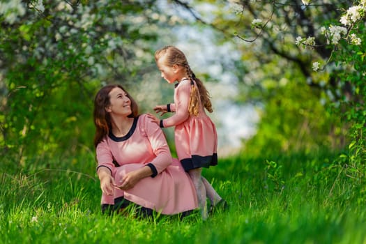 mother and daughter in nature in identical dresses