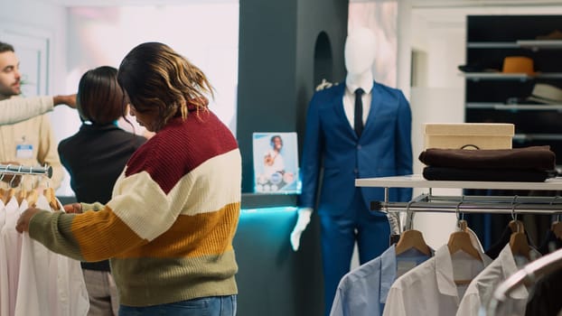 Boutique client analyzing modern clothes on hangers, looking to buy new fashion collection to improve wardrobe. Casual woman checking clothing store merchandise in shopping center.