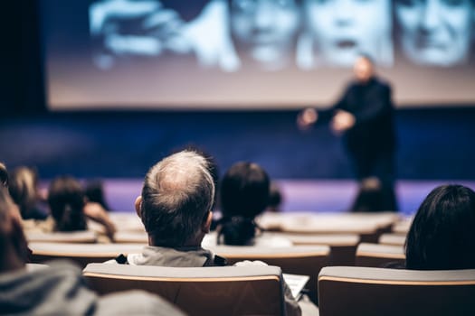 Speaker giving a talk in conference hall at business event. Rear view of unrecognizable people in audience at the conference hall. Business and entrepreneurship concept