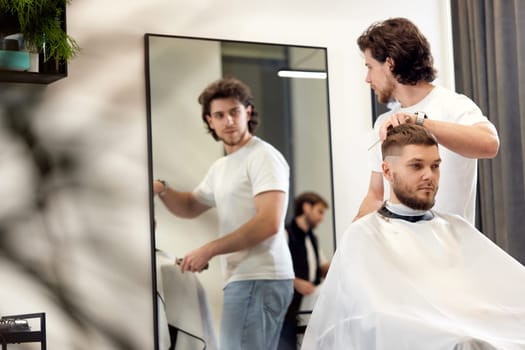 handsome young man visiting professional hairstylist in barber shop
