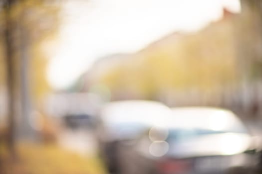 Autumn season bokeh background. Abstract city blur along the road with cars