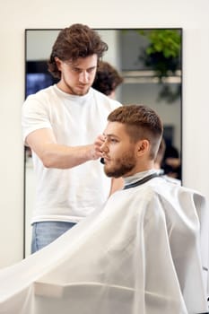 handsome young man visiting professional hairstylist in barber shop