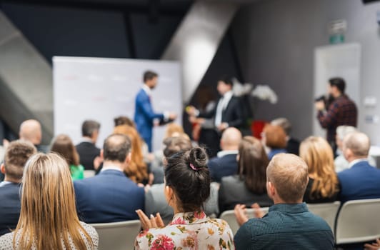 Business team leader receiving award prize at best business project competition event. Business and entrepreneurship award ceremony theme. Focus on unrecognizable people in audience