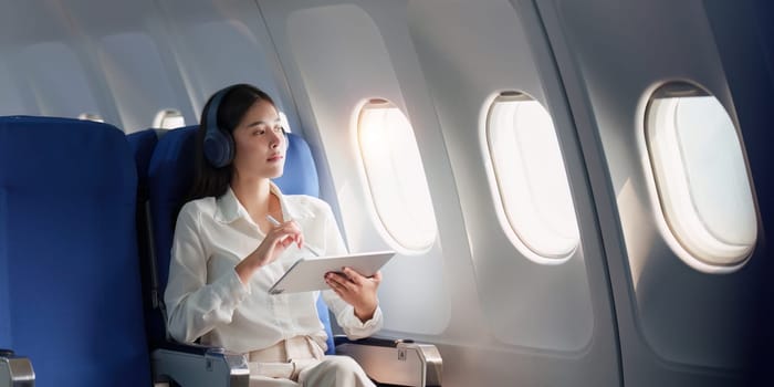 Beautiful Asian businesswoman working with digital tablet in aeroplane. working, travel, business concept.