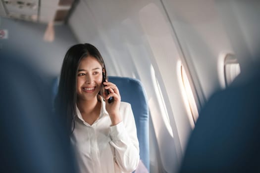 Traveling and technology. Flying at first class. Pretty young businees woman using smartphone while sitting in airplane...