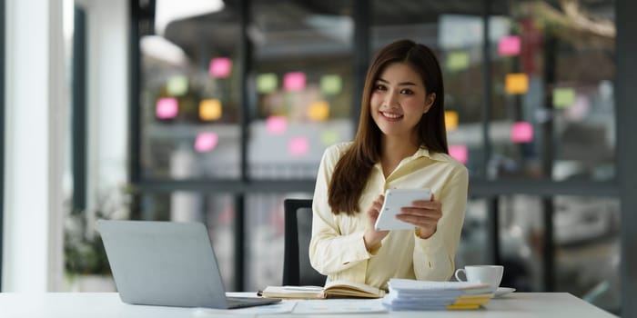 Beautiful Asian Banker or Accountant makes financial report and tax, analyzes profits. Accountant checks status of financial.