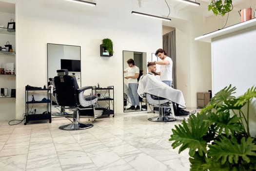 Professional barber during work with man client in modern light barber shop.