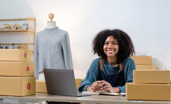 Young woman freelancer sme business online shopping look at camera with cardboard box on table at home - Business online shipping and delivery concept..