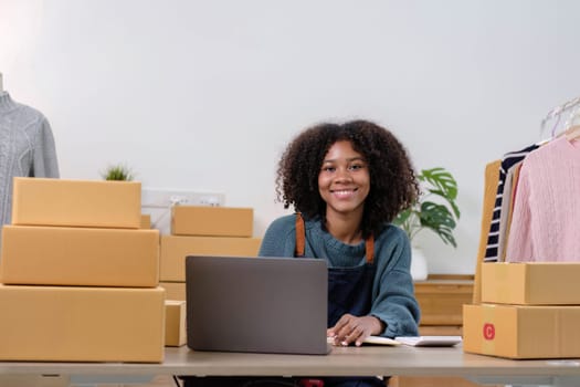 Young woman freelancer sme business online shopping look at camera with cardboard box on table at home - Business online shipping and delivery concept..