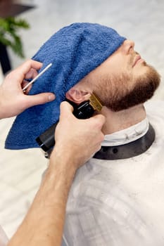 Barber shaving handsome bearded man in barber shop.