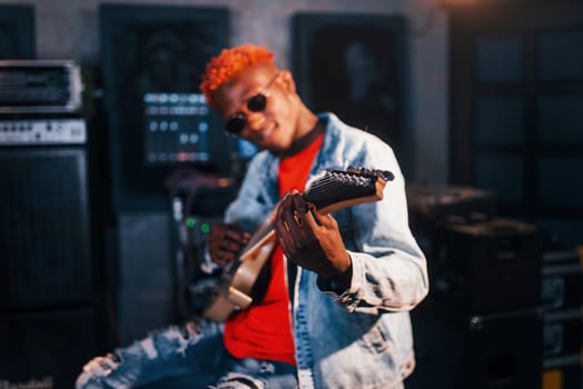 Plays guitar. Young african american performer rehearsing in a recording studio.