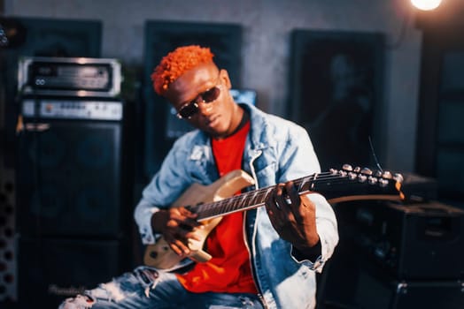 Plays guitar. Young african american performer rehearsing in a recording studio.