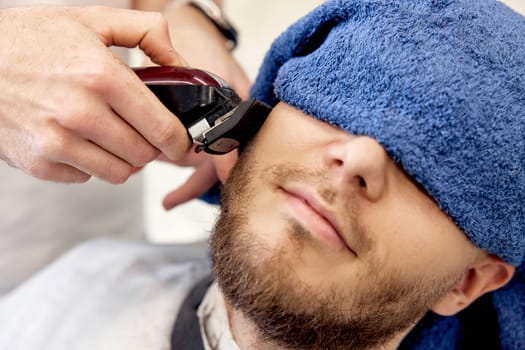 male hands of barber with hair clipper, close up.