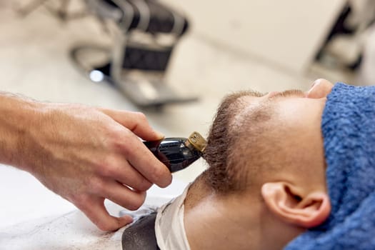 Barber shaving handsome bearded man in barber shop.