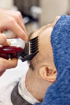 male hands of barber with hair clipper, close up.