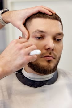Barber shaving bearded man with retro knife in barber shop. close-up