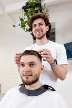 Barber and satisfied bearded man in front of the mirror in barber shop