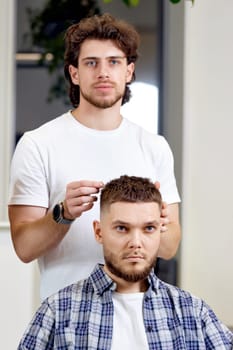 Barber and satisfied bearded man in front of the mirror in barber shop