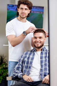 Barber and satisfied bearded man in front of the mirror in barber shop