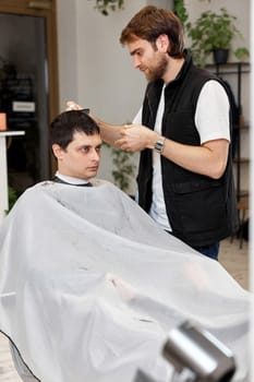 Hairstylist serving handsome caucasian man in barber shop.