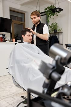 Hairstylist serving handsome caucasian man in barber shop.