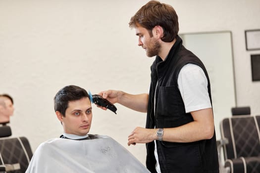 Barber shaving handsome caucasian man in barber shop.