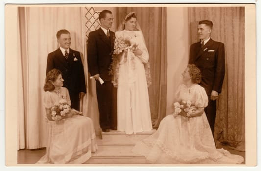 PRAGUE, THE CZECHOSLOVAK REPUBLIC - APRIL 18, 1942: Vintage photo shows newlyweds and bridesmaids. Retro black and white photography with sepia effect.