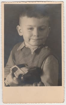 MAGDEBURG, GERMANY - CIRCA 1940s: Vintage photo shows boy holds toy car. Black and white photography
