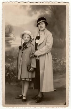 OLBERNHAU, GERMANY - NOVEMBER 1934: Vintage photo shows woman wears ladies hat - cloche hat and her daughter. Retro black and white studio photography.