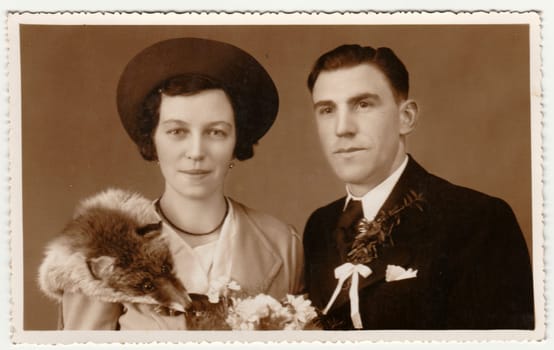 PRAGUE, THE CZECHOSLOVAK REPUBLIC - CIRCA 1940s: Vintage photo shows newlyweds. Wedding ceremony - bride and groom. Bride wears fox scarf. Retro black and white photography with sepia effect.