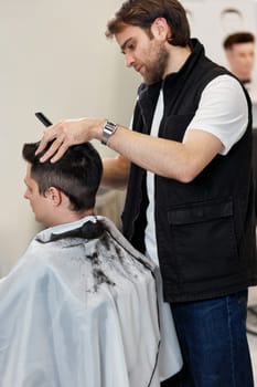 Barber shaving handsome caucasian man in barber shop.