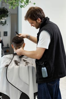 Barber shaving handsome caucasian man in barber shop.