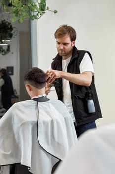 Barber shaving handsome caucasian man in barber shop.