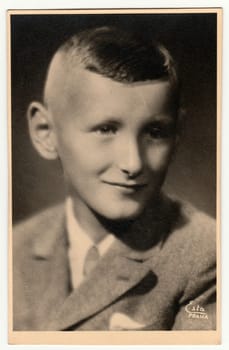 PRAGUE, THE CZECHOSLOVAK REPUBLIC - CIRCA 1940s: Vintage photo shows a young boy portrait in a photography studio. Retro black and white studio photography with sepia effect.