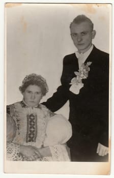 DOLNI VESTONICE, THE CZECHOSLOVAK REPUBLIC - CIRCA 1940s: Vintage photo shows couple in a photography studio. Woman wears a folk costume. Retro black and white studio photography.