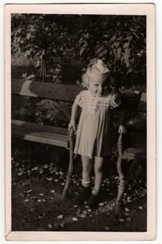 THE CZECHOSLOVAK REPUBLIC - SEPTEMBER 8, 1940: Vintage photo shows a small girl between park benches. Retro black and white photography.