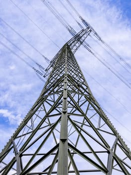 Tall steel power pole with many steel beams and struts and power lines taken from diagonal below