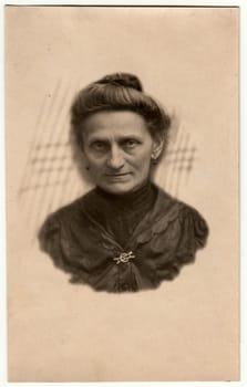 GERMANY - CIRCA 1930s: Vintage photo shows elderly woman - portrait in a photography studio. Woman with Edwardian hairstyle. Retro black and white studio photography with sepia effect. Head is drawn to body.