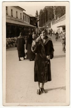 THE CZECHOSLOVAK REPUBLIC - CIRCA 1930s: Vintage photo shows woman wears a fur coat, goes for a walk Retro black and white phortgraphy.