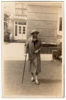 LUHACOVICE, THE CZECHOSLOVAK REPUBLIC - CIRCA 1930s: Vintage photo shows woman with a stick in the spa resort. Woman goes for a walk. Retro black and white phorography.