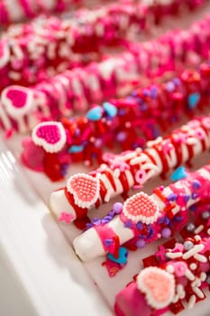 Chocolate-covered pretzel rods decorated with heart-shaped sprinkles for Valentine's Day.