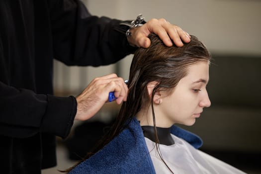 male hairdresser is combing the hair of the female client. hairdresser doing hair to his client woman