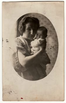 PRAHA - PRAGUE, THE CZECHOSLOVAK REPUBLIC - SEPTEMBER 15, 1927: Vintage photo shows mother cradles a small baby. Retro black and white photography. Circa 1930s.